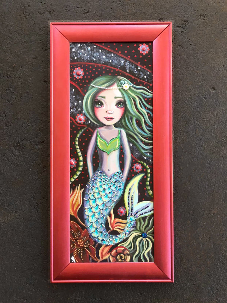 A whimsical mermaid painting in a rose gold coloured wood frame. Lots of rhinestones and sparkles added.